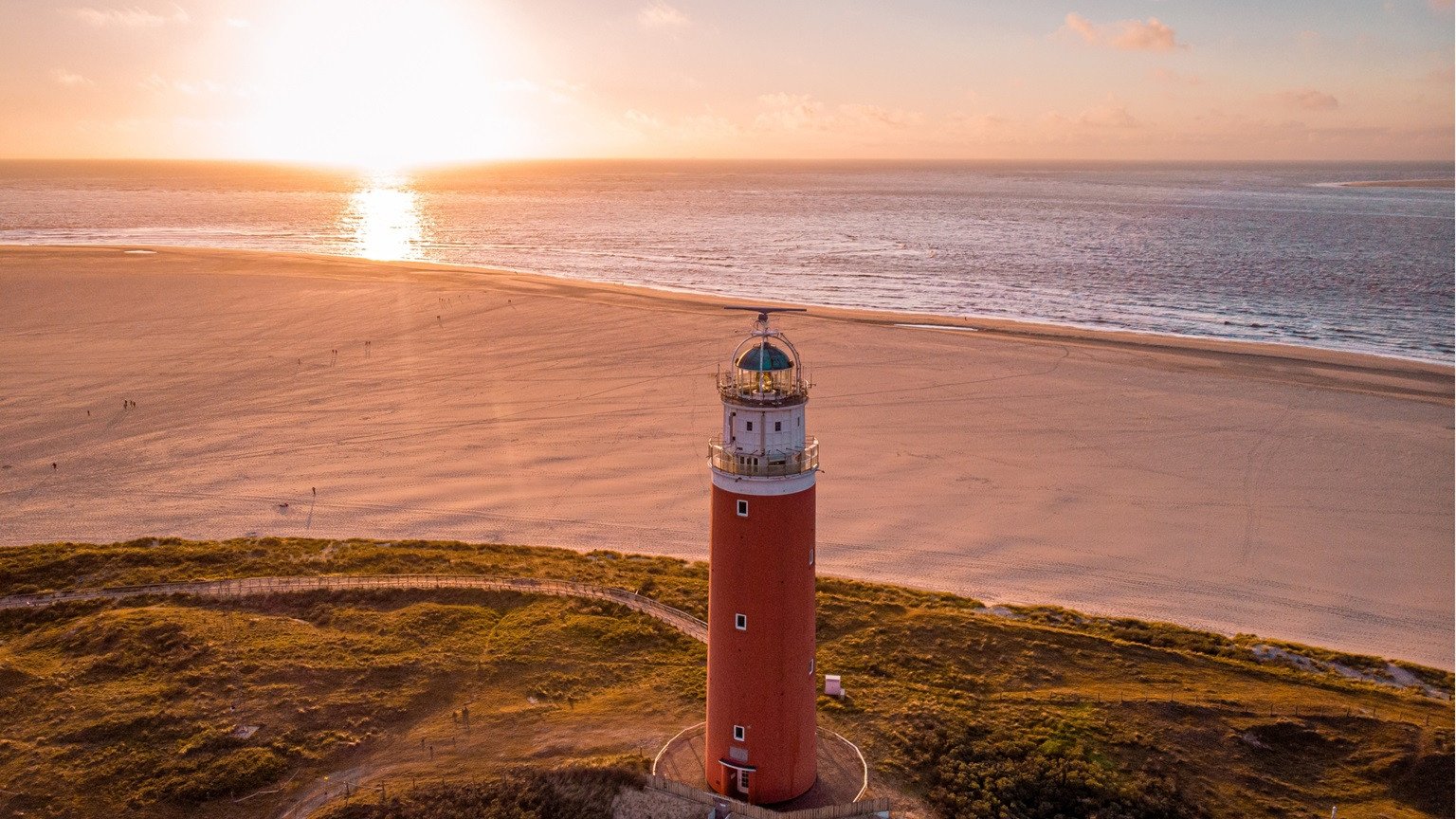 Vuurtoren op Texel bij zonsondergang met uitzicht over strand en zee.