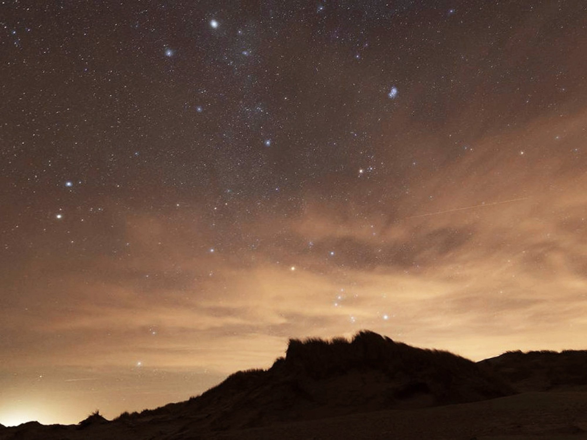 Sterrenhemel boven de duinen van Oosterend op Terschelling, onderdeel van het Dark Sky Park, met heldere sterren en een zacht verlichte horizon.
