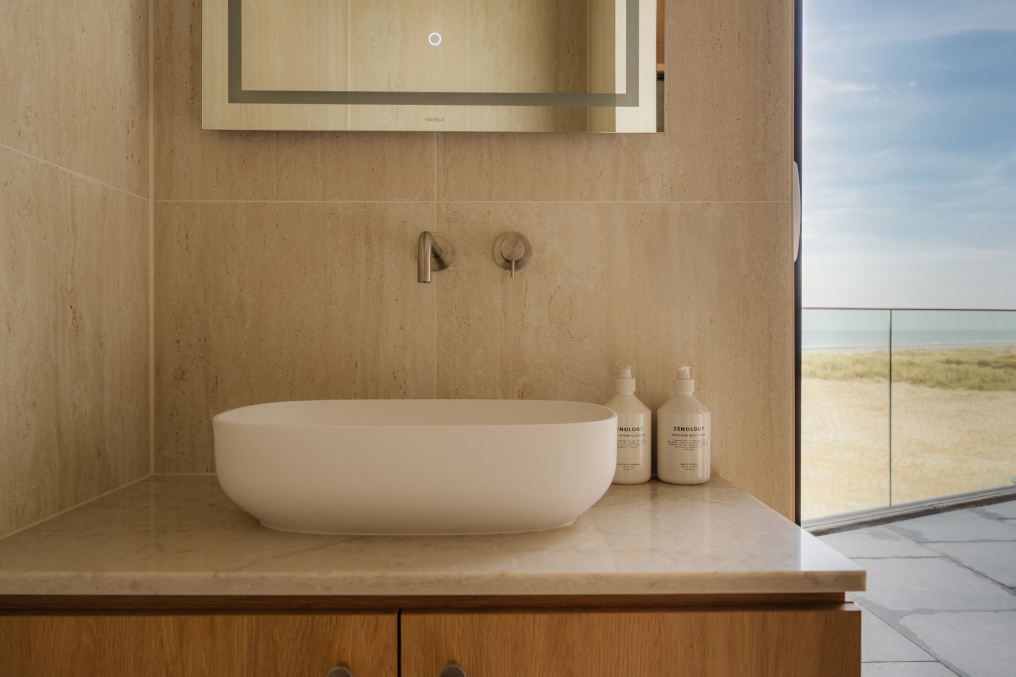 Badkamer met wastafel en uitzicht op de duinen bij Elements Terschelling.