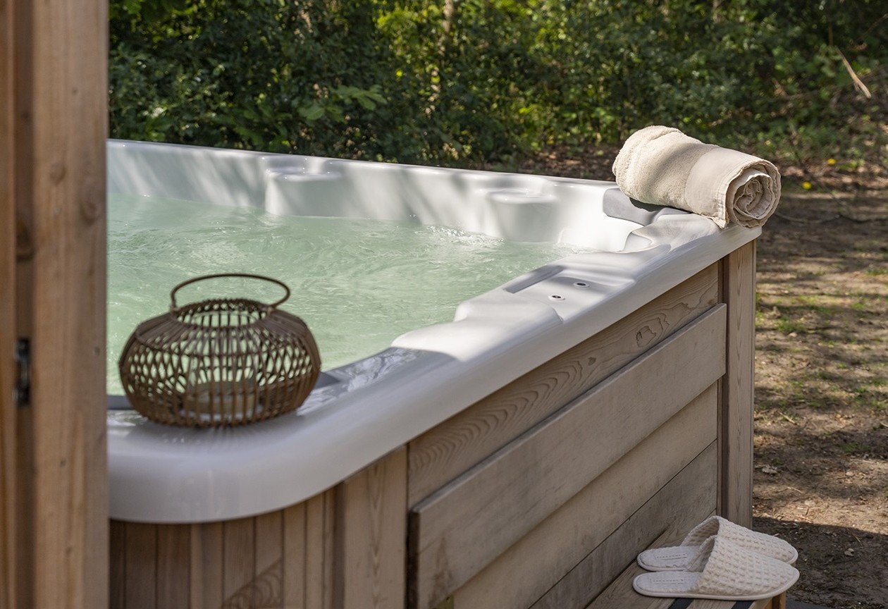 Privé whirlpool in een groene tuin in de Gooilanden, onderdeel van een wellnessverblijf.