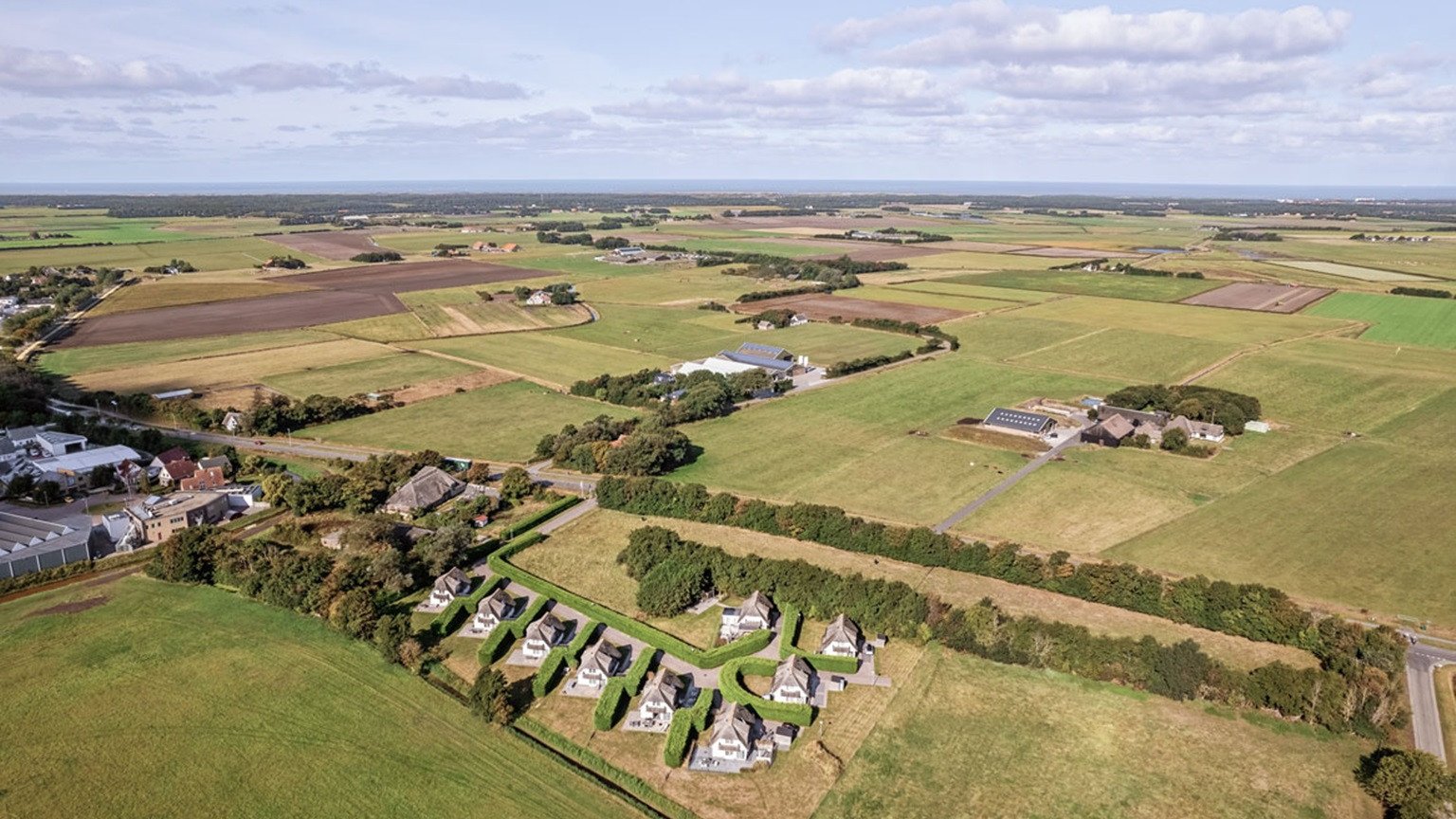 Luchtfoto van vakantiepark Waddenduyn op Texel met villa’s in groene omgeving.