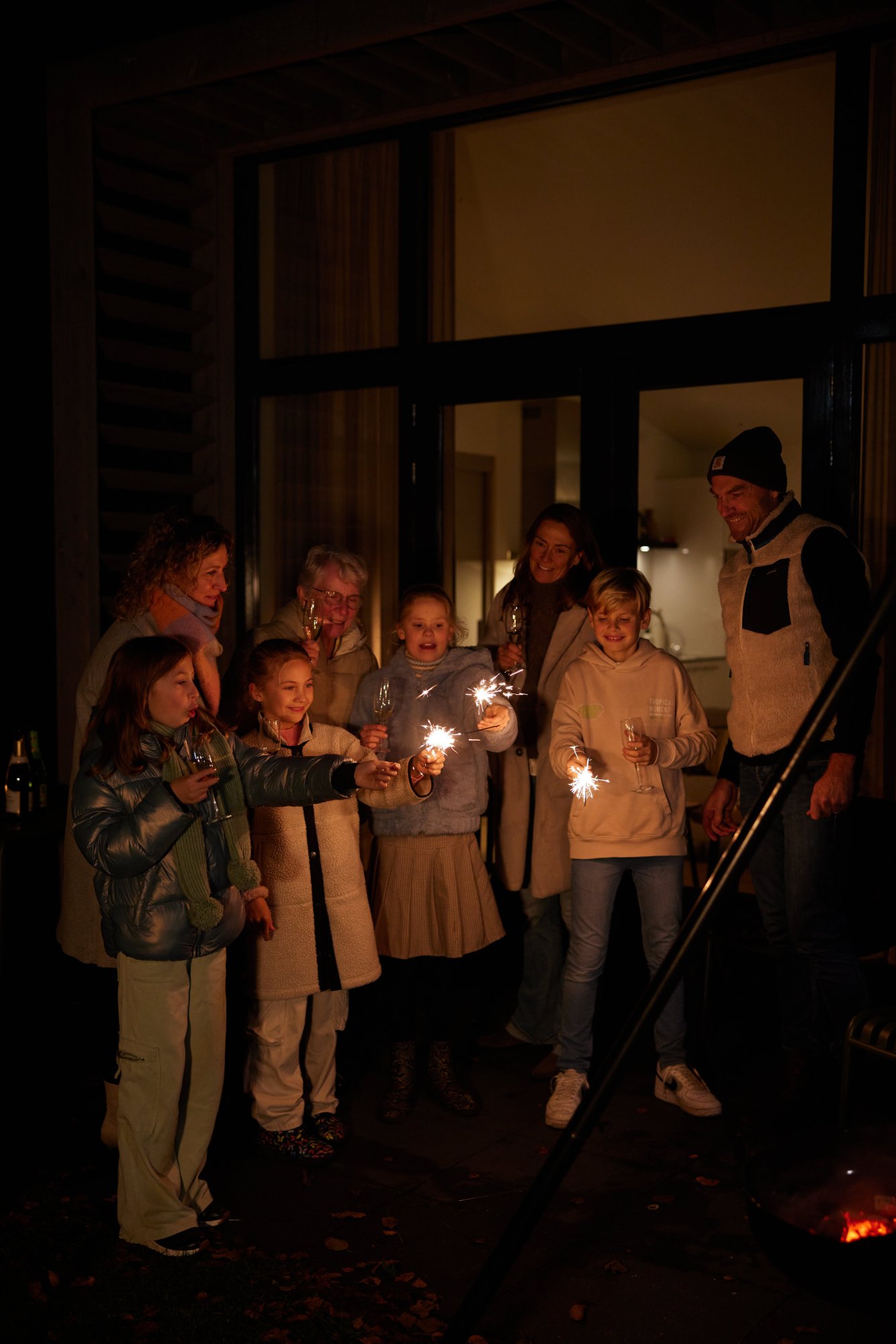 Familie viert oud en nieuw bij een vakantiehuis met sterretjes in de avond.