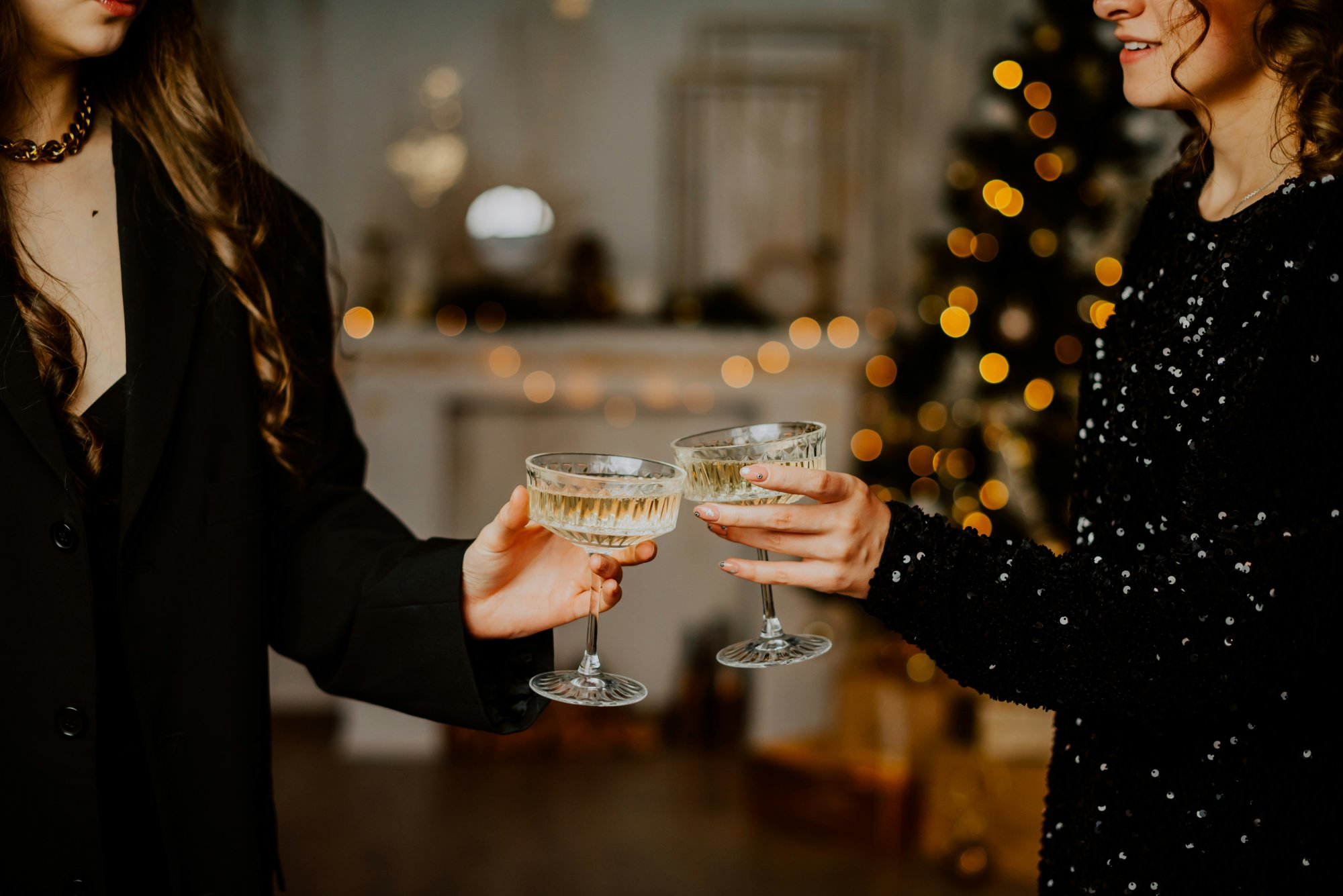 Twee personen proosten met een glas bubbels tijdens oud en nieuw.