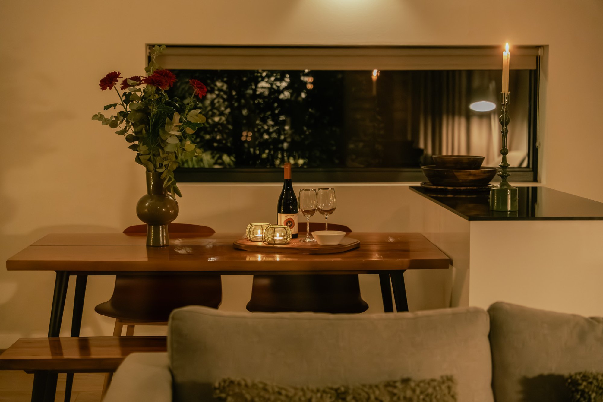 Sfeervolle eettafel in een vakantiehuis met kaarslicht, wijn en bloemen.