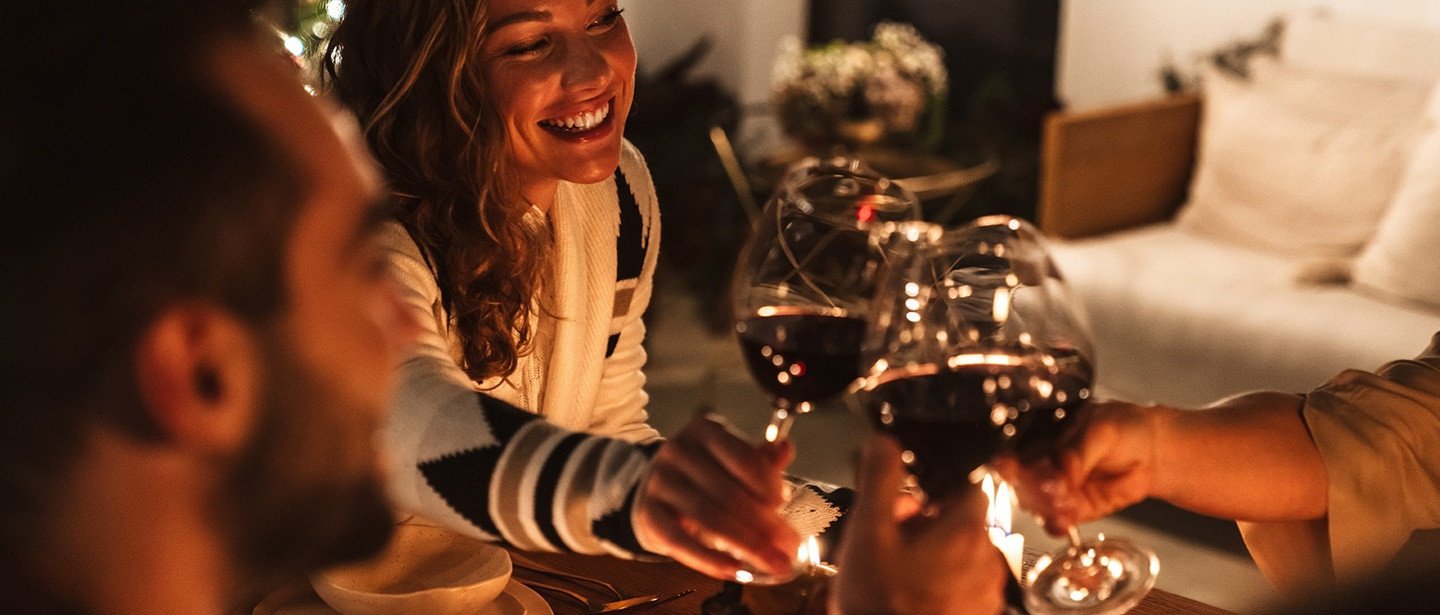 Gezelschap proost met glazen rode wijn tijdens een sfeervol diner.